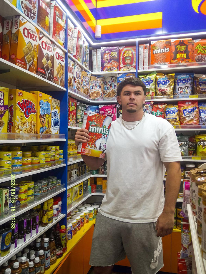 A guy holding a cereal box in a bright supermarket aisle, flash photo on the Love Goggles digicam