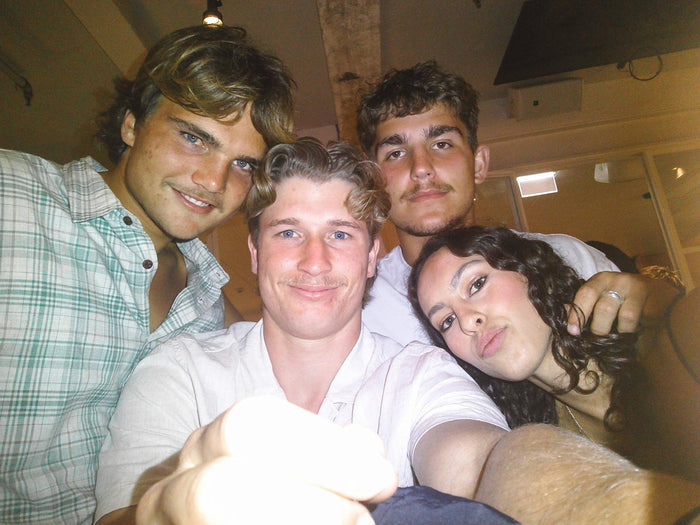 Friends packed into a flash-lit group selfie at a bar, shot on the Love Goggles digicam