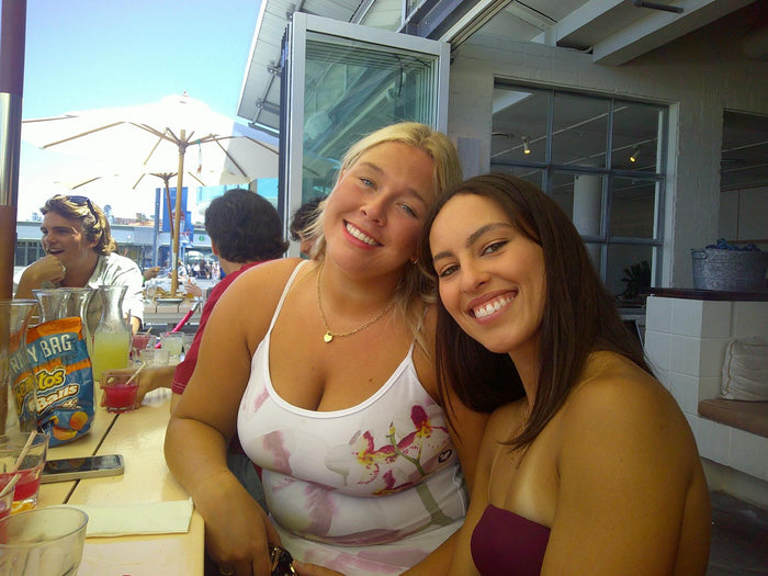 Two friends smiling close together at an outdoor bar, flash photo on the Love Goggles digicam